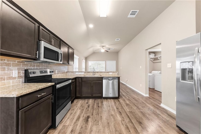 109 Dove Ct, Navasota, TX 77868 - kitchen featuring stainless steel appliances, washer and clothes dryer, a sink, vaulted ceiling, and a peninsula