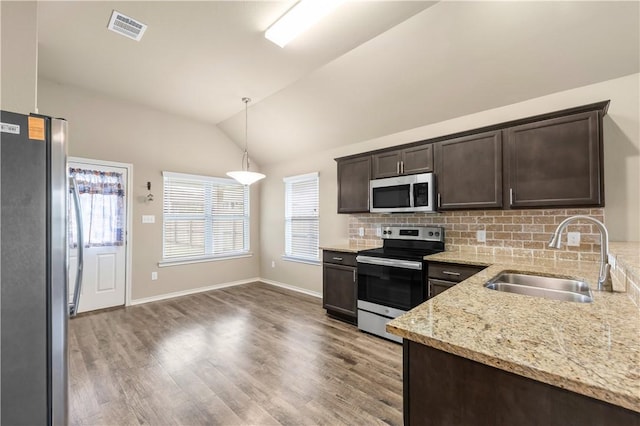 109 Dove Ct, Navasota, TX 77868 - kitchen featuring appliances with stainless steel finishes, a sink, dark brown cabinetry, healthy amount of natural light, and vaulted ceiling