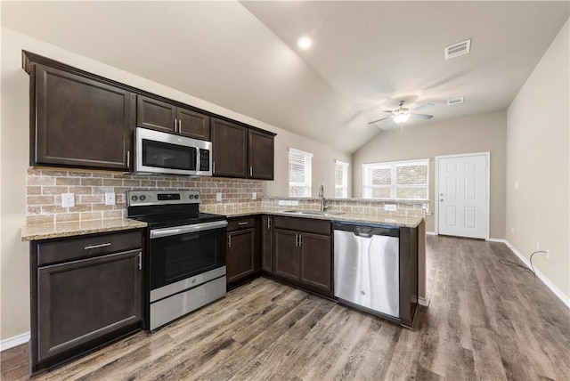 109 Dove Ct, Navasota, TX 77868 - kitchen featuring appliances with stainless steel finishes, decorative backsplash, a peninsula, dark brown cabinets, and wood finished floors