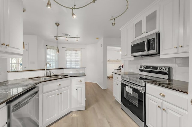 kitchen with appliances with stainless steel finishes, sink, decorative light fixtures, light hardwood / wood-style flooring, and white cabinets