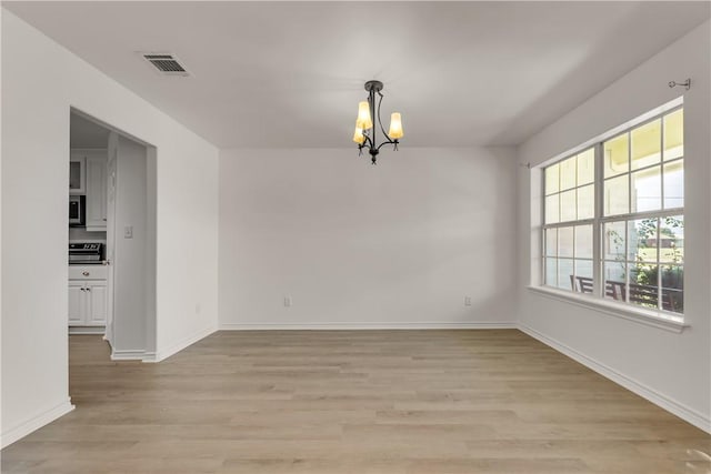 unfurnished room with a chandelier and light hardwood / wood-style floors