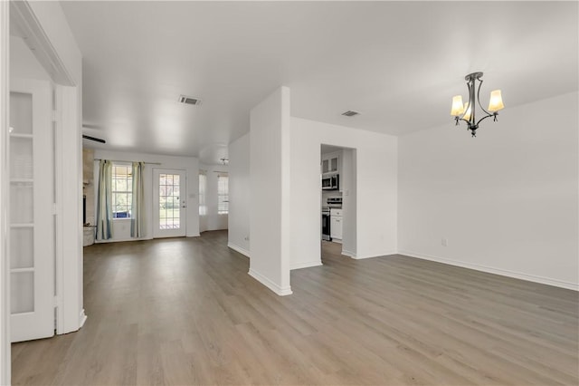 unfurnished living room featuring an inviting chandelier and light wood-type flooring