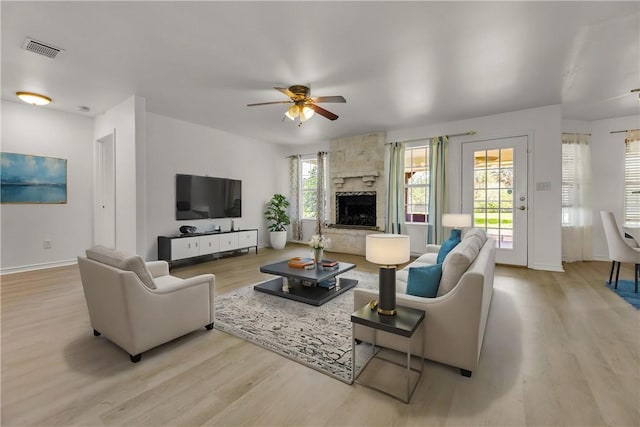 living room featuring ceiling fan, a fireplace, and light wood-type flooring