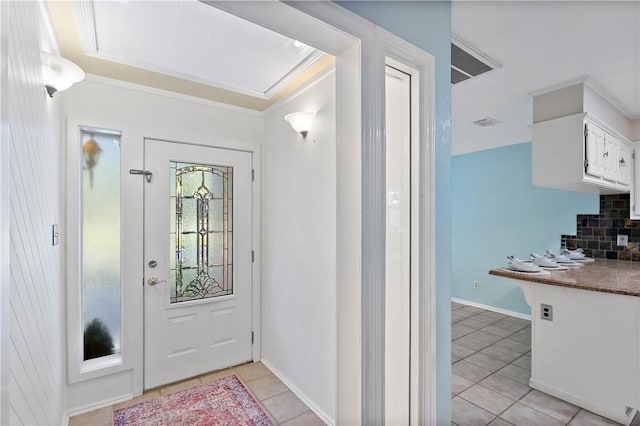 tiled foyer entrance featuring crown molding