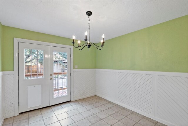 interior space with an inviting chandelier, light tile patterned flooring, a textured ceiling, and french doors