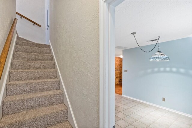 staircase with tile patterned flooring and an inviting chandelier