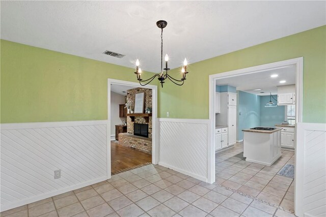 unfurnished dining area with a chandelier, light tile patterned floors, and a fireplace