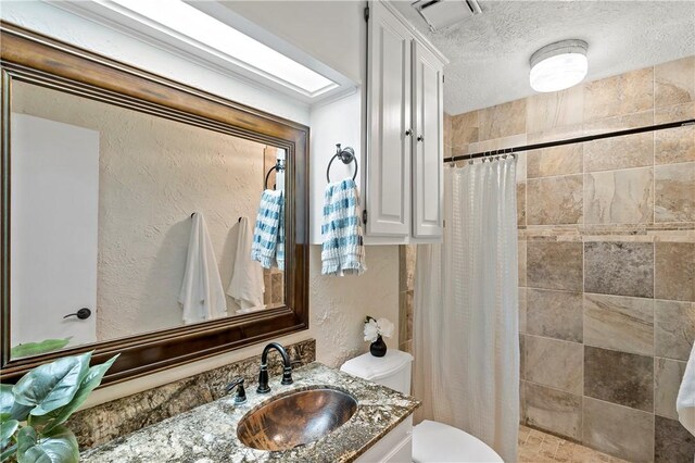 bathroom featuring vanity, curtained shower, toilet, and a textured ceiling