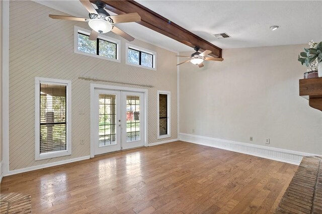 unfurnished living room featuring light hardwood / wood-style floors, high vaulted ceiling, and french doors