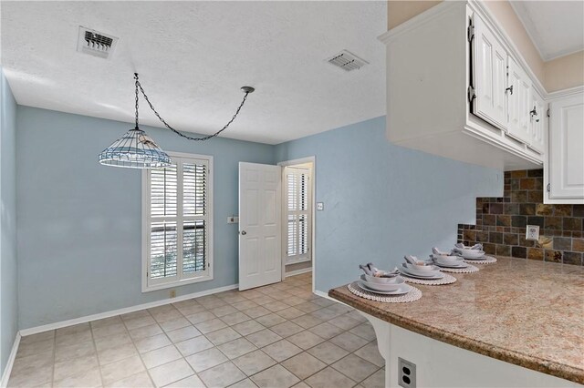 kitchen featuring hanging light fixtures, light tile patterned floors, backsplash, a textured ceiling, and white cabinets