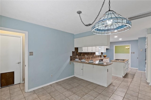 kitchen with backsplash, white cabinets, decorative light fixtures, kitchen peninsula, and a chandelier