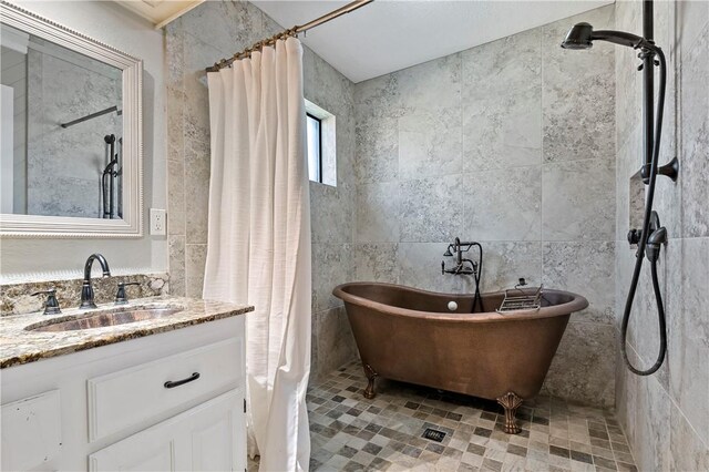 bathroom featuring plus walk in shower, vanity, and tile walls