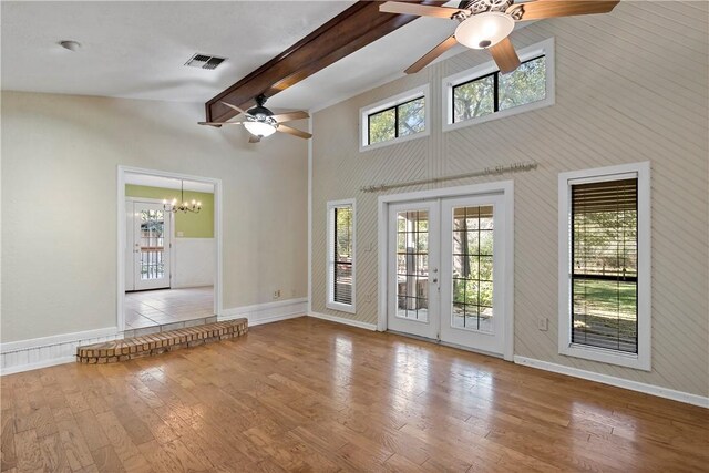 unfurnished living room with beam ceiling, high vaulted ceiling, light hardwood / wood-style flooring, and french doors