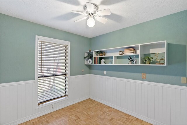 spare room featuring ceiling fan, a textured ceiling, and light parquet flooring