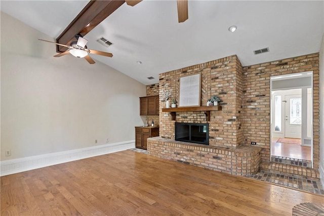 unfurnished living room featuring vaulted ceiling with beams, ceiling fan, hardwood / wood-style floors, and a brick fireplace