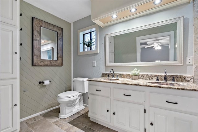 bathroom with vanity, toilet, ceiling fan, and wooden walls