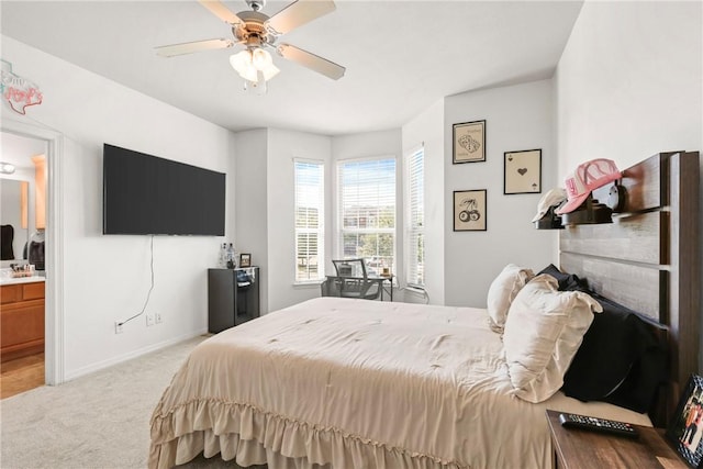 carpeted bedroom with ensuite bath, a ceiling fan, and baseboards