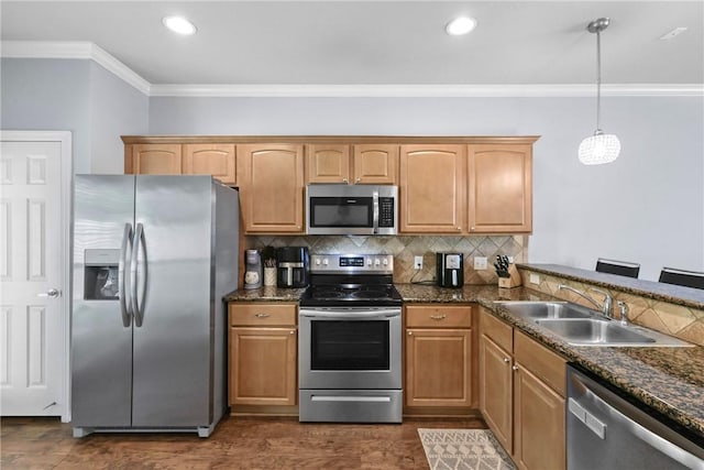 kitchen with pendant lighting, ornamental molding, a sink, stainless steel appliances, and backsplash