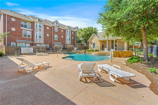 community pool with a patio and fence