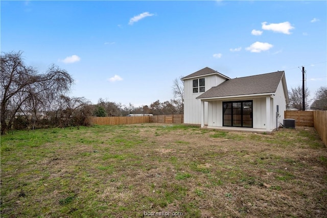 rear view of property featuring cooling unit and a lawn