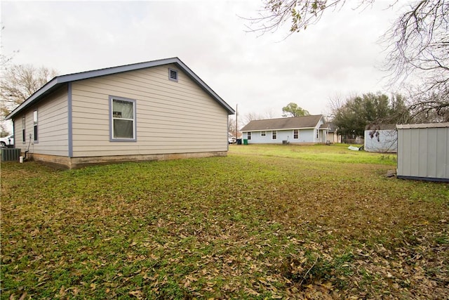 view of home's exterior featuring cooling unit, a yard, and a storage unit