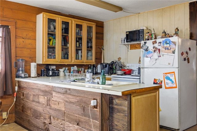 kitchen featuring white appliances, wood walls, and kitchen peninsula