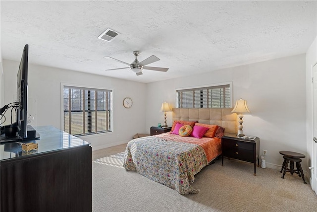 carpeted bedroom featuring ceiling fan and a textured ceiling