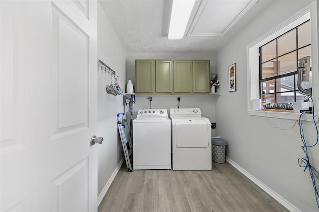 laundry room featuring a textured ceiling, cabinets, light wood-type flooring, and washer and clothes dryer