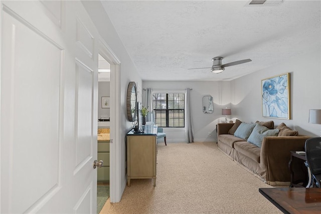 carpeted living room featuring ceiling fan and a textured ceiling