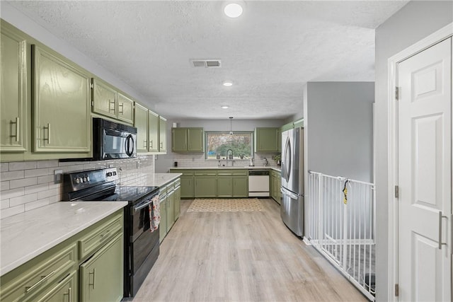 kitchen with green cabinets, light stone counters, light hardwood / wood-style flooring, decorative backsplash, and black appliances