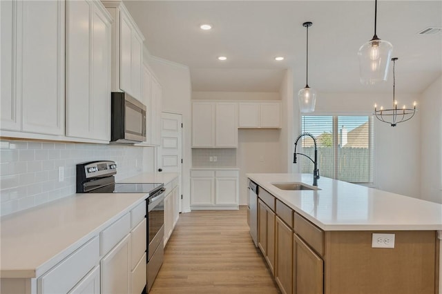 kitchen with appliances with stainless steel finishes, white cabinetry, a large island, and sink