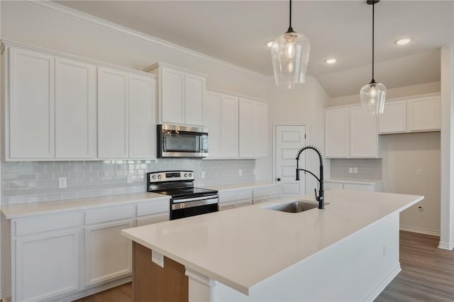 kitchen featuring appliances with stainless steel finishes, a kitchen island with sink, sink, decorative light fixtures, and white cabinetry