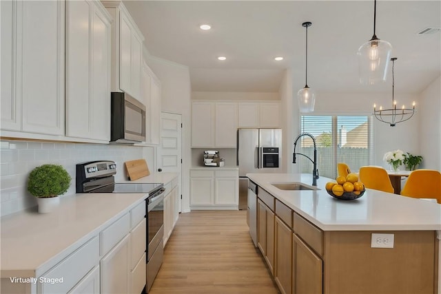 kitchen with a large island, sink, white cabinets, and stainless steel appliances