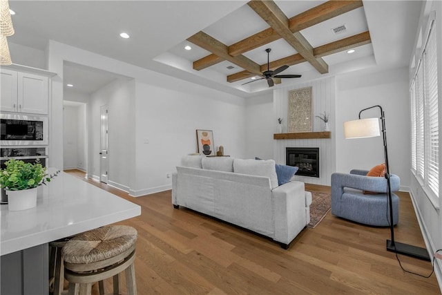 3576 Chantilly Path, Bryan, TX 77808 - living area featuring coffered ceiling, ceiling fan, light wood finished floors, a large fireplace, and beam ceiling