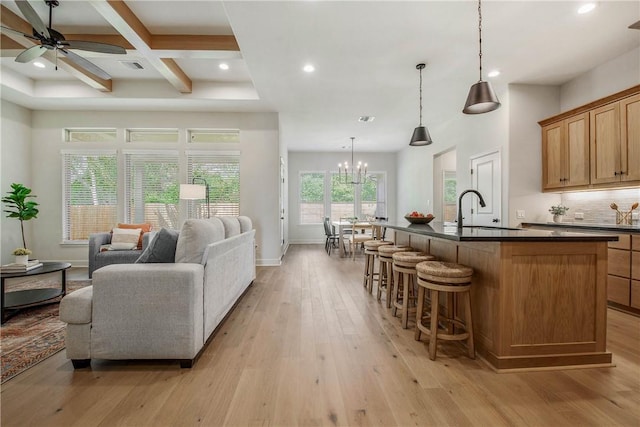 living room featuring plenty of natural light, sink, light wood-type flooring, beam ceiling, and coffered ceiling