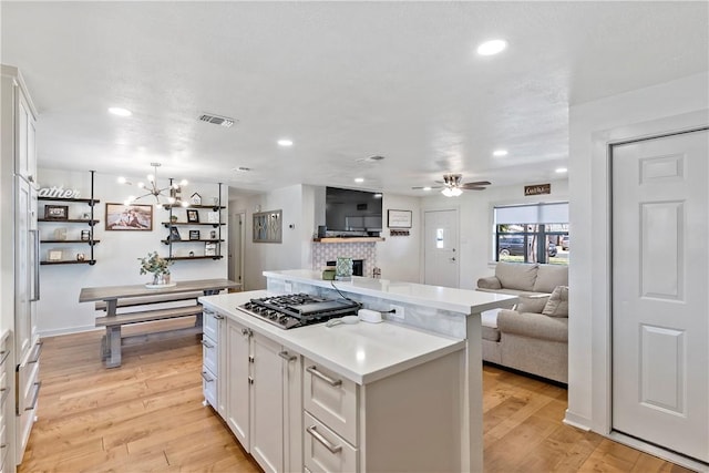 kitchen with a center island, white cabinets, visible vents, and light wood finished floors