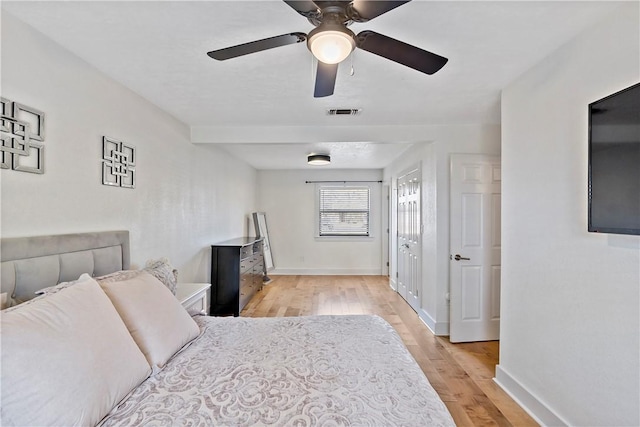 bedroom with a ceiling fan, light wood-type flooring, visible vents, and baseboards