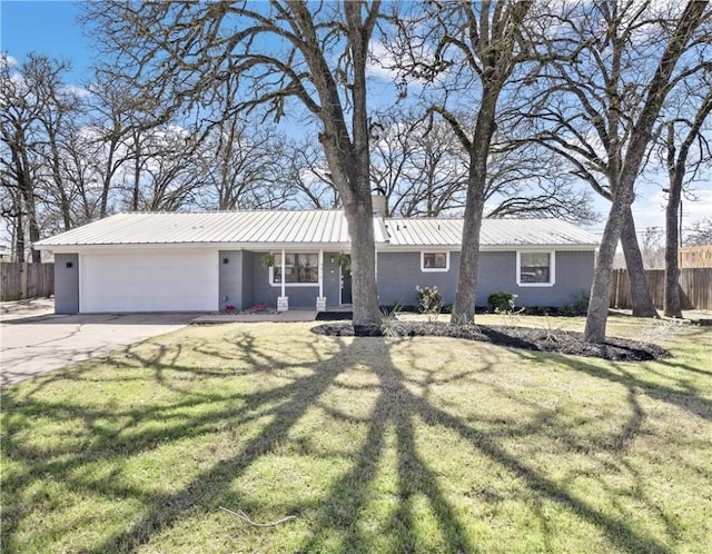 ranch-style house featuring a garage, concrete driveway, metal roof, fence, and a front lawn