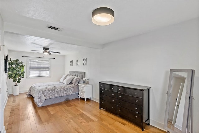 bedroom featuring baseboards, light wood-type flooring, visible vents, and a ceiling fan