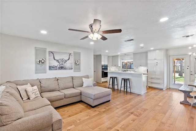 living room featuring recessed lighting, visible vents, ceiling fan, and light wood-style flooring