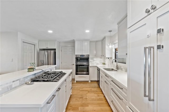 kitchen featuring light wood finished floors, appliances with stainless steel finishes, a center island, a sink, and backsplash