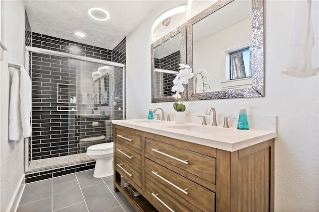 full bathroom with double vanity, toilet, a sink, a shower stall, and tile patterned floors