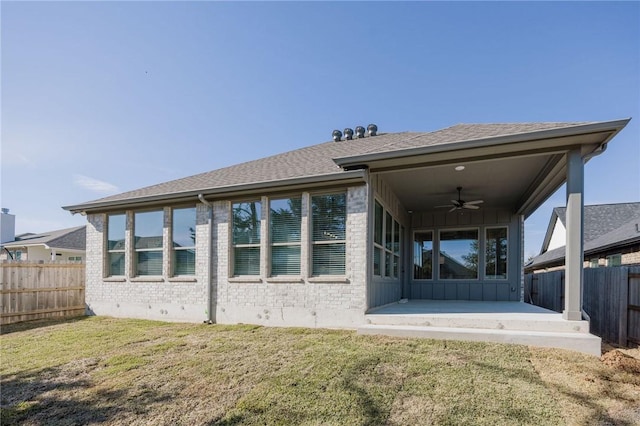 rear view of property featuring ceiling fan, a patio area, and a lawn