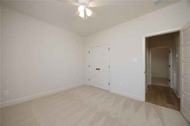 unfurnished bedroom featuring ceiling fan, light colored carpet, and a closet