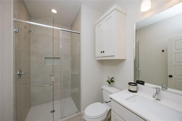 bathroom with vanity, toilet, and a shower with door