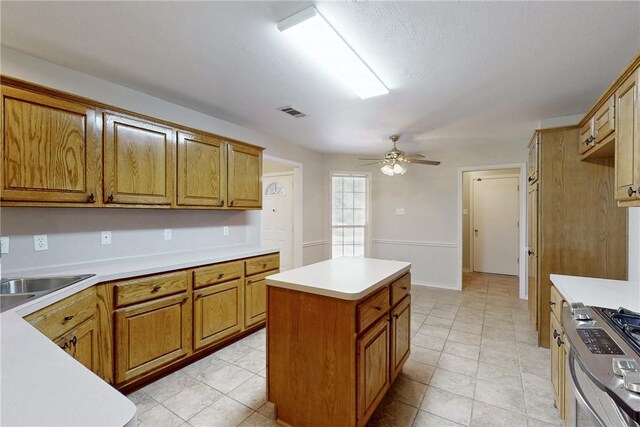 2600 Greenberry Cir, College Station, TX 77845 - kitchen with ceiling fan, stainless steel range with gas cooktop, brown cabinets, and light countertops