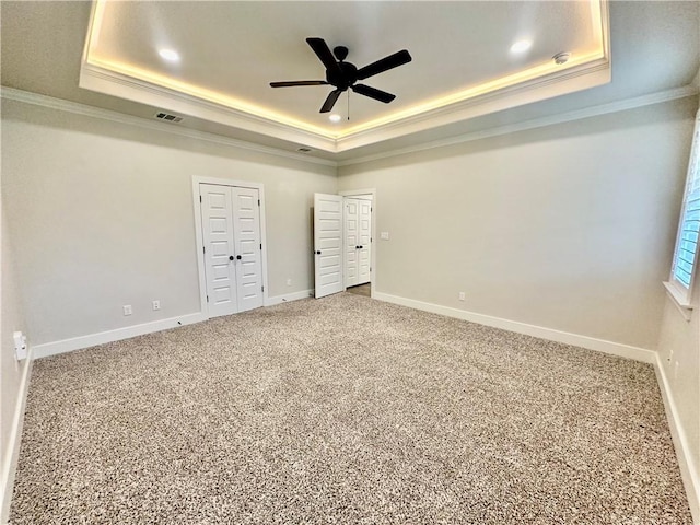 unfurnished bedroom featuring ceiling fan, a raised ceiling, carpet floors, and crown molding