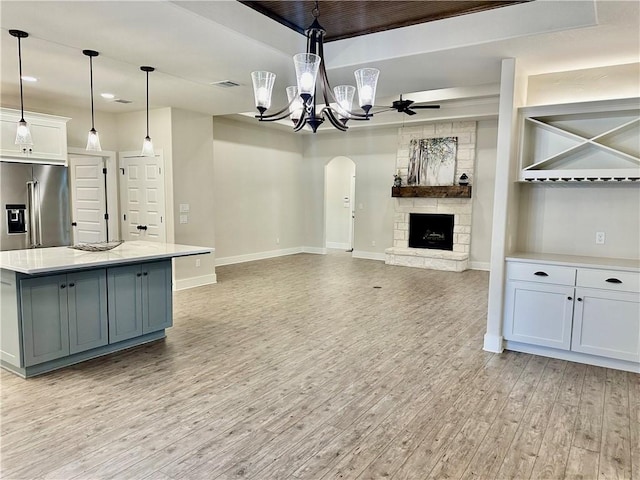 kitchen with light wood-type flooring, high quality fridge, pendant lighting, white cabinets, and a center island