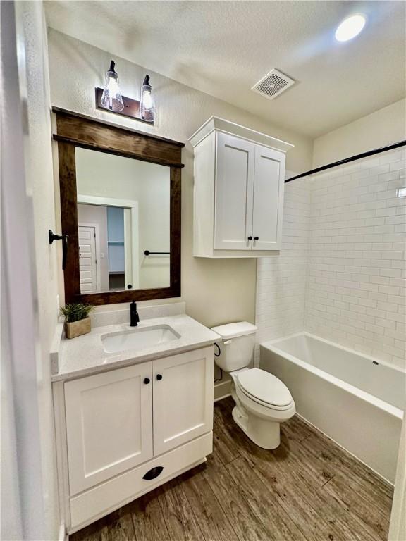 full bathroom featuring vanity, toilet, wood-type flooring, and tiled shower / bath