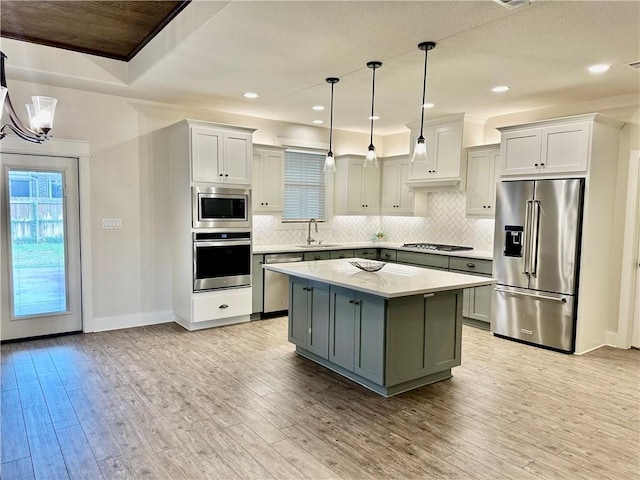 kitchen with a center island, sink, hanging light fixtures, stainless steel appliances, and light hardwood / wood-style floors